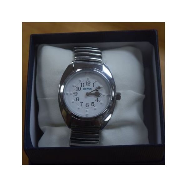 Chrome quartz watch displayed on watch pillow in product box.